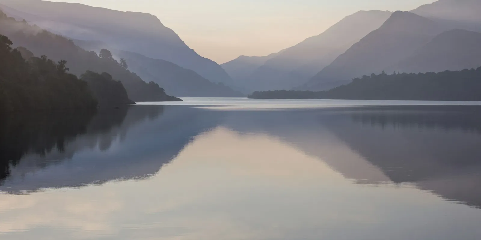 A still lake at the foot of a mountain on a calm day