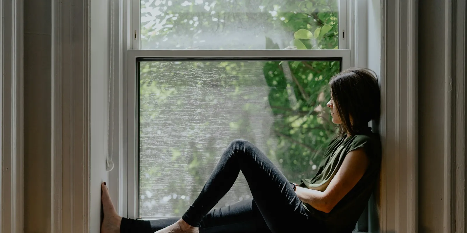 A woman sitting quietly on a window sill